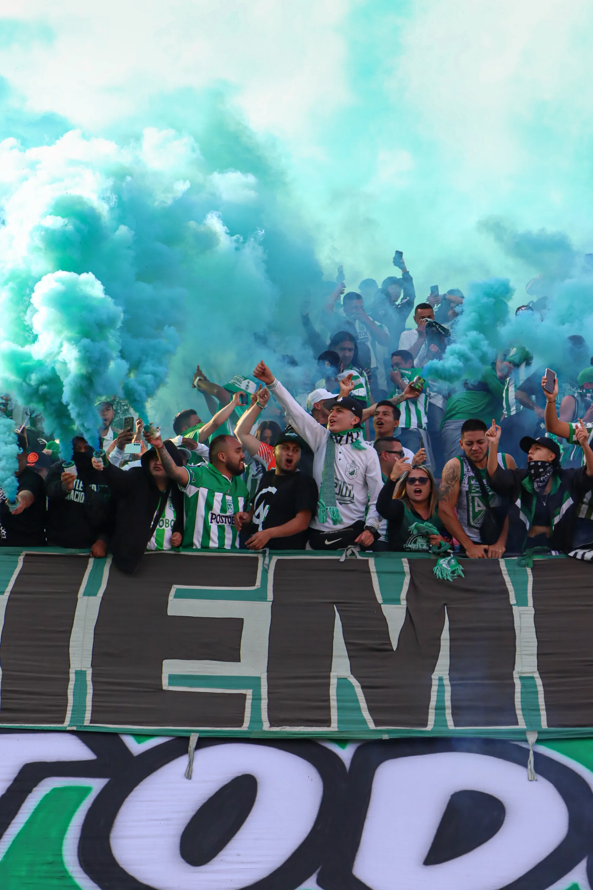 Humo verde de la hinchada y torre de luces del estadio